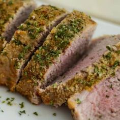 sliced meat sitting on top of a white plate covered in parmesan and seasoning