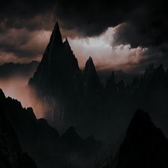 the mountains are covered in dark clouds as they stand on top of a mountain range