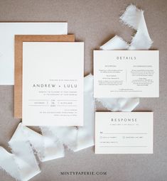 the wedding stationery is laid out on top of torn up pieces of white paper