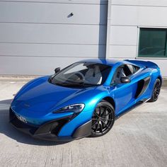 a blue sports car parked in front of a building