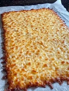 a large cheesy pizza sitting on top of a white piece of wax paper