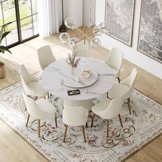 a dining room table with white chairs and a rug on the floor in front of it