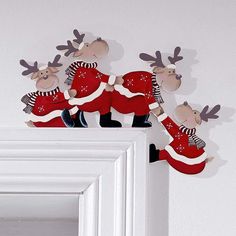 three wooden reindeer figures on top of a white frame in front of a white wall