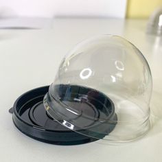 a clear glass dome on top of a black plastic plate with the word o in it