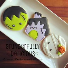 three decorated cookies sitting on top of a white plate