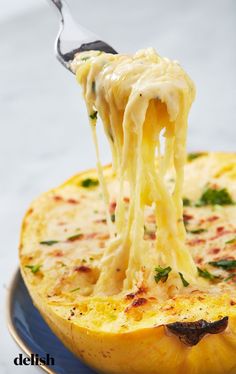 a fork full of spaghetti being lifted from an omelet in a blue dish