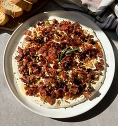 a white plate topped with a pizza covered in toppings next to slices of bread