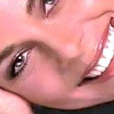 a close up of a woman smiling with her hand on her face