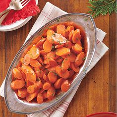 carrots in a bowl on a table next to a fork and napkin with utensils