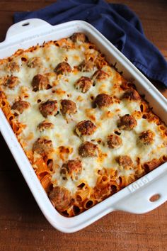 a casserole dish with meatballs and cheese in it on a wooden table