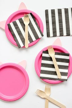 pink plates with black and white striped napkins, forks and utensils on them