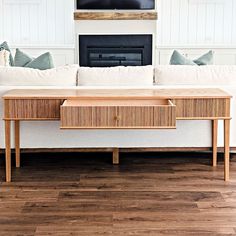 a living room with a white couch and wooden coffee table in front of a fireplace