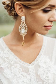 a woman wearing gold and white earrings