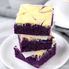 three pieces of purple cake sitting on top of a white plate next to two cups of coffee