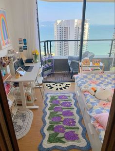 a bedroom with a bed, desk and large window overlooking the ocean in front of it