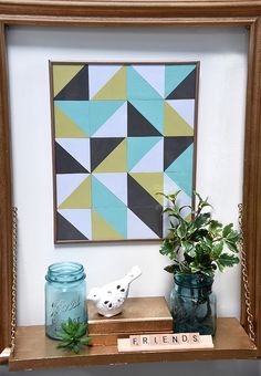 a wooden shelf topped with vases filled with plants next to a framed art piece