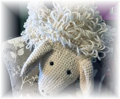 a crocheted sheep with white wool on it's head sitting on a chair