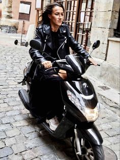 a woman sitting on top of a motor scooter in the middle of an alleyway