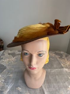 Antique brown  braided straw hat. It has a small round crown and small brim.  Around the crown is a yellow cotton  cloth and rust netting band. On one side is a brown velvet bow. The hat is an oval shape or more egg shape with the fro t being wider.At the back underneath is 2 green and brown silk flower shapes with brown velvet ribbon connecting them.If hat is tipped to one side the rear flowers can be seen but if set straight, they would not be seen very well.  Inside is lined in black fabric and there is an elastic cord. Measurements Inside circumference is about 18 inches Front to back 12 inches Across 10.5 inches  Crown 1.5 inches high Brim is 3.5 inches in the front and about 2 inches in the back. Condition - good   Brown straw is good and yellow cloth band is good. Rust netting is to Brimmed Brown Hat For Vintage Events, Brown Brimmed Hat For Vintage Events, Victorian Short Brim Hat For Vintage Events, Victorian Costume Hat With Curved Brim, Victorian Hat With Short Brim For Church, Vintage Brimmed Top Hat For Costume, Vintage Short Brim Top Hat For Costume, Vintage Brown Hat Bands For Summer, Brimmed Hats For Kentucky Derby Costume