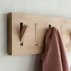 a wooden coat rack with hooks and clothes hanging from it's sides on a wall