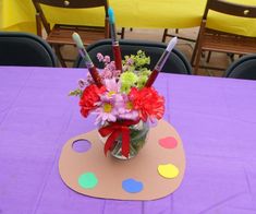 a vase filled with lots of flowers on top of a purple table covered in polka dots