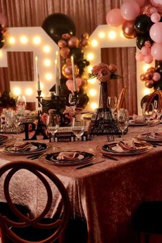 a table set for a party with balloons and candles in the shape of the eiffel tower