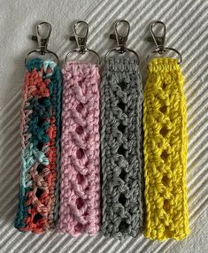 four crocheted keychains are lined up on a bed