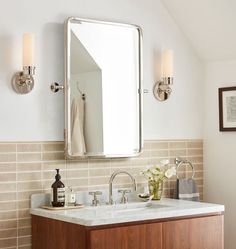 a bathroom sink with a mirror above it and two lights on the wall next to it