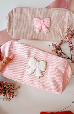 two purses with bows on them sitting next to each other, one pink and one white