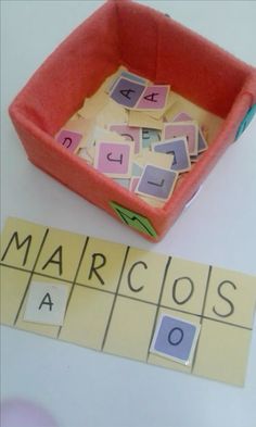 a pink box filled with cut out letters next to a scrabble game