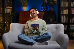 a man sitting on a couch with headphones in his ears and holding a tablet