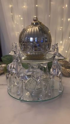 glass figurines are sitting on top of a clear plate with a domed lid