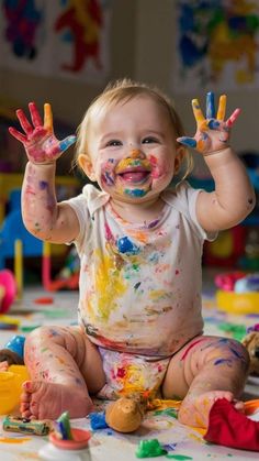 a baby is sitting on the floor with paint all over his body and hands in front of him