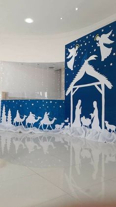 paper cut nativity scene displayed in large room with blue walls and white flooring