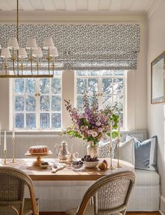 a dining room table with two chairs and a vase filled with flowers