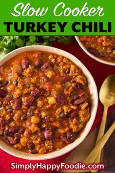 two bowls of slow cooker turkey chili on a red cloth with gold spoons