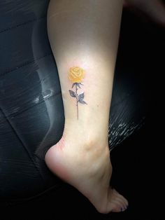 a small yellow rose tattoo on the ankle