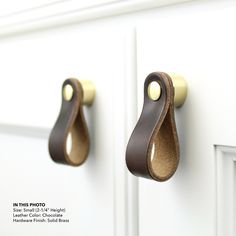 two brown leather handles on a white cabinet