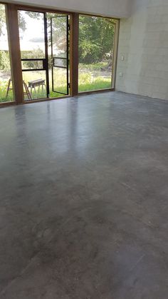 an empty room with concrete floors and large windows