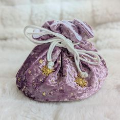 This starry multi pocket dice bag is made with a mauve purple and white velvety fabric. It is soft to the touch and will keep your dice nice and cozy. There is no design other than that cute gold stars, so this bag isn't game symbol specific. The bag has strong cord drawstrings accented with gold solar charms at the ends.  Inner bag space is about 9 x 4.5 inches, plenty of room for several sets of dice, there are 6 inner pockets that will hold 3 to 4 standard dice sets and 1 large middle pocket that can hold about 20 sets. That's a lot of easily transportable and organized dice storage! Dice Storage, Mauve Purple, Organization Decor, Dice Bag, Purple And White, Gold Stars, Large Bags, Purple And Black, Glow In The Dark