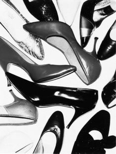 black and white photograph of various pairs of high heeled shoes on top of each other