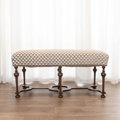 a bench sitting on top of a hard wood floor next to a white curtained window