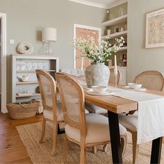 a dining room table with chairs and a vase filled with flowers