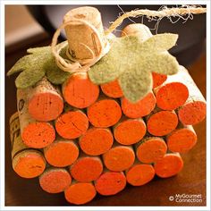 an orange wine cork decoration with leaves on the top, sitting on a wooden table