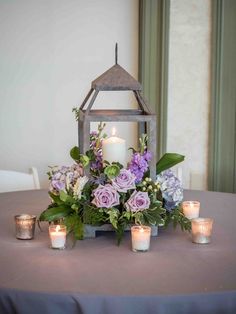 a table topped with candles and flowers next to a small lantern filled with greenery