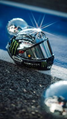 a helmet sits on the ground in front of another helmet that has been placed upside down