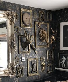 an ornately decorated wall in a living room with framed pictures and decorative animal heads on the wall