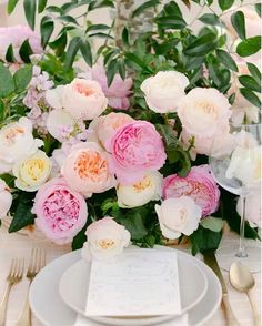 the table is set with white and pink flowers, silverware, and napkins