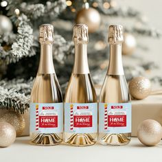 three bottles of champagne sitting next to a christmas tree