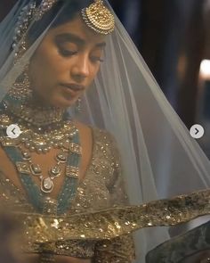 a woman wearing a gold and blue bridal gown with a veil over her head